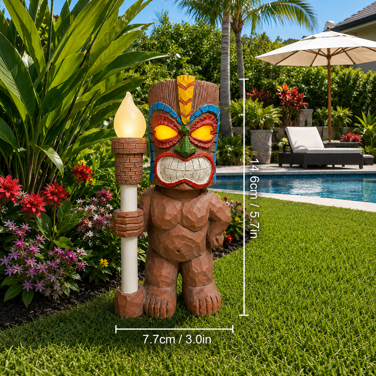 Solar tiki totem statue light holding a glowing torch beside tropical plants and a backyard pool
