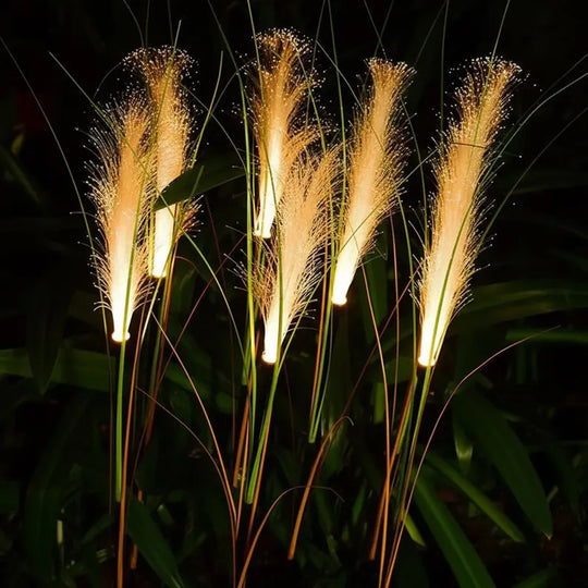 Reed-shaped solar stake lights glowing along a garden path after dark