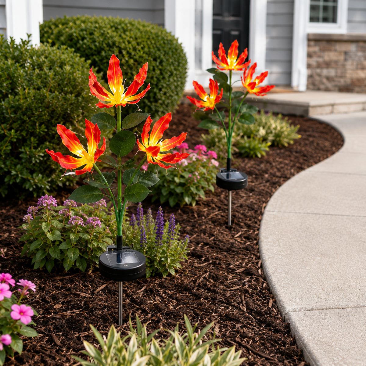 Solar fire lily stakes adding color to a compact flower bed in daylight
